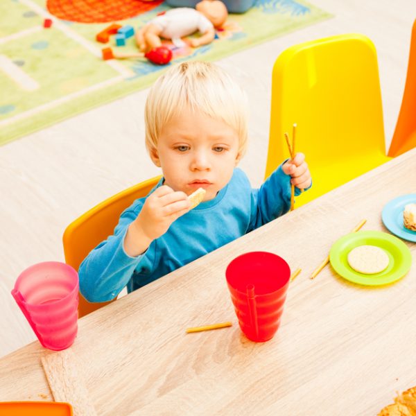 Children are sitting at the table with lunch and eating fruits and cakes